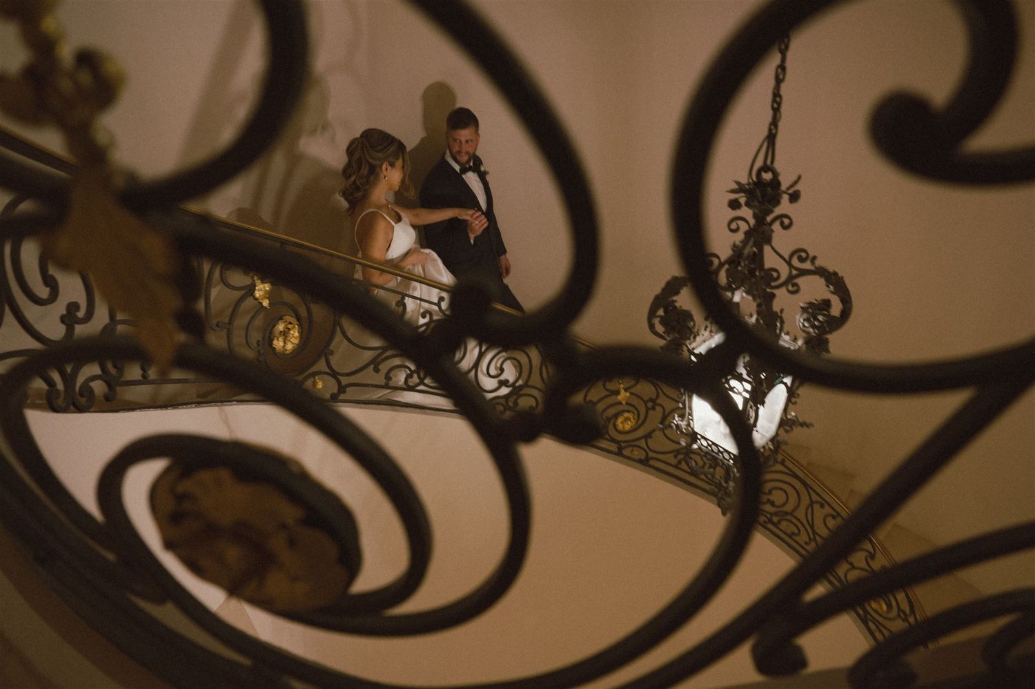Artistic wedding photo framed through ornate wrought iron railings.