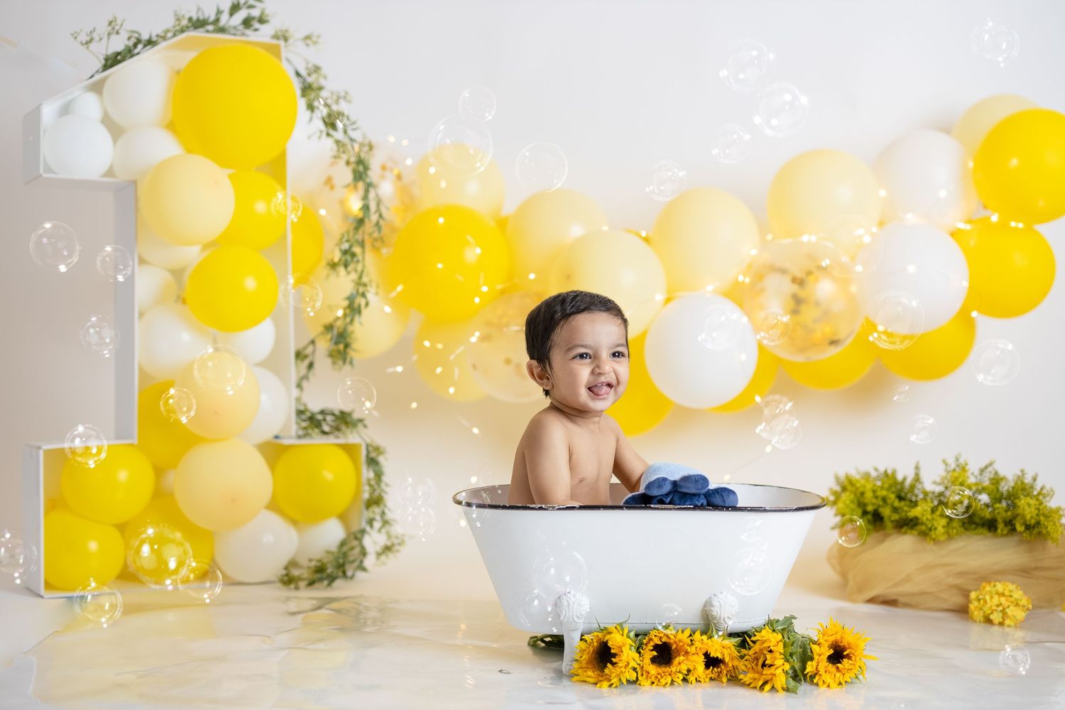 Bath time themed first birthday photo with yellow balloons and sunflower decorations.