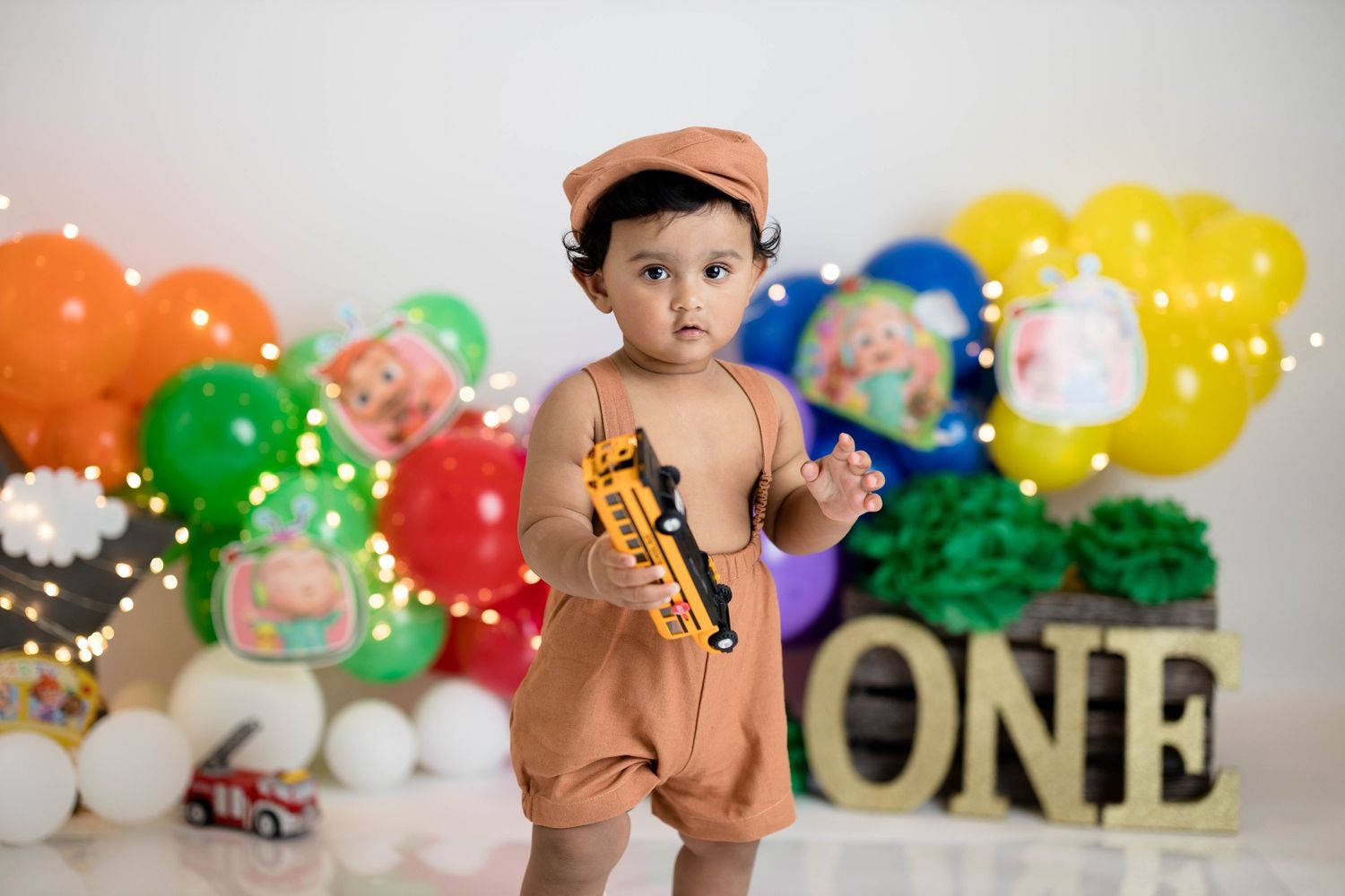 Birthday celebration with colorful balloon backdrop and gold ONE letters.