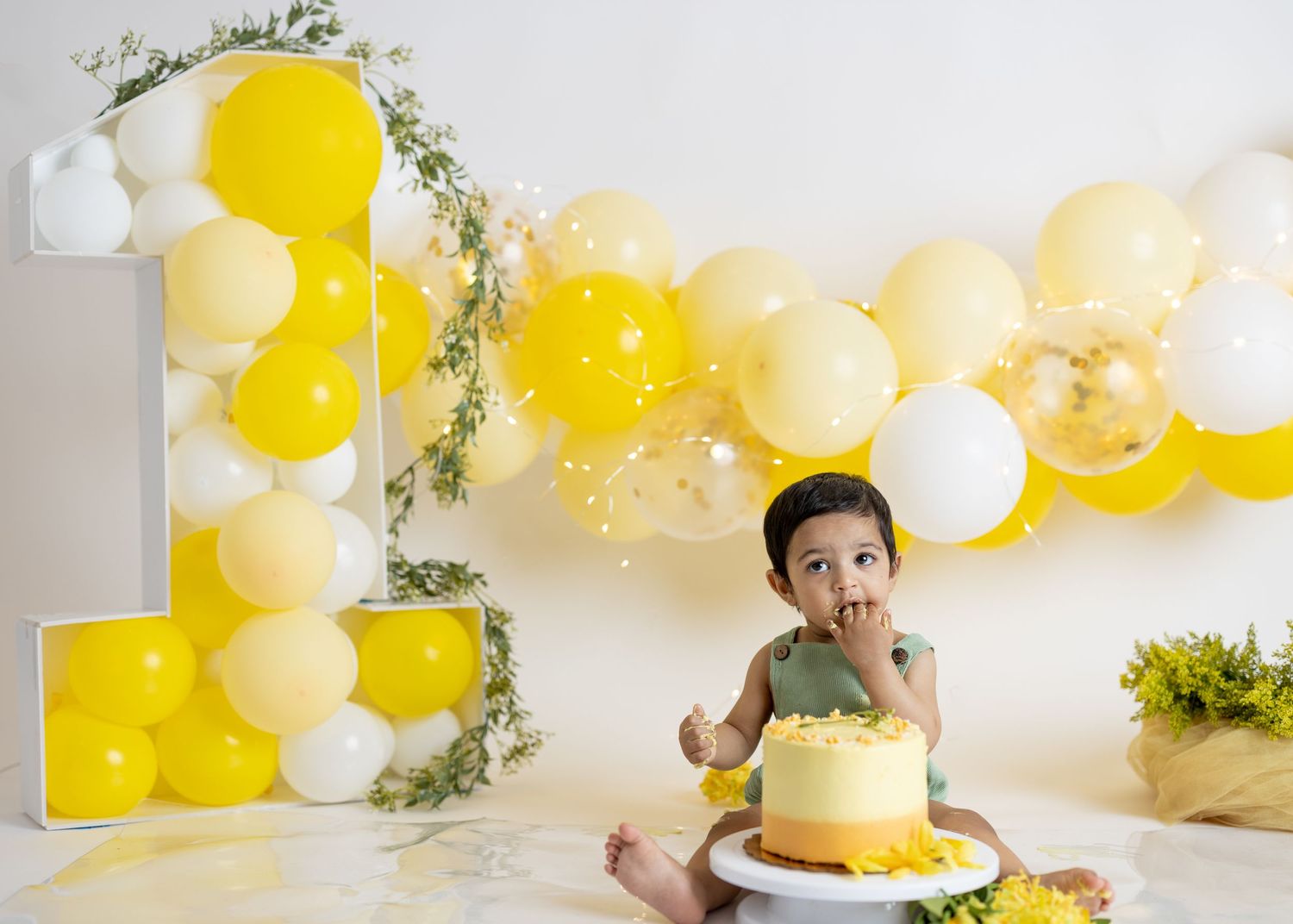 Yellow and white balloon arch with number one decoration for first birthday celebration.