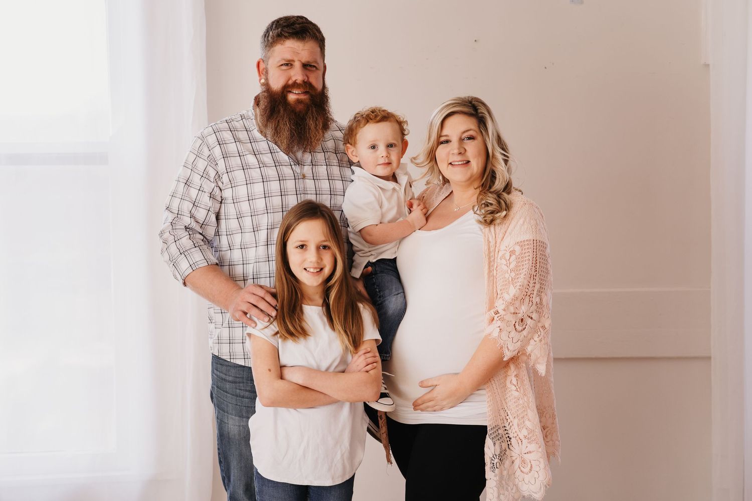Indoor family portrait featuring parents and children in coordinated white and neutral outfits.