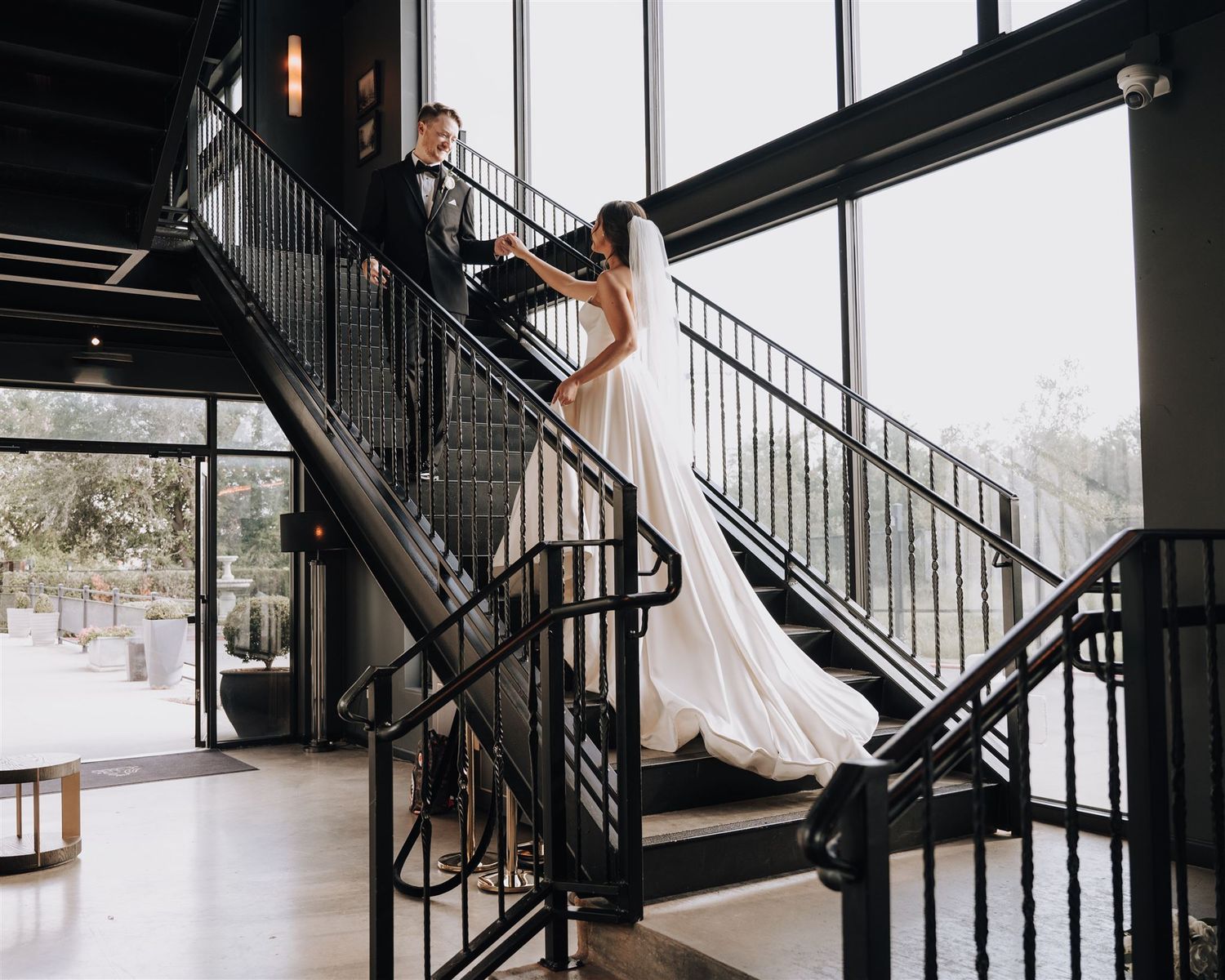 An elegant wedding photo on a modern black metal staircase with natural lighting.