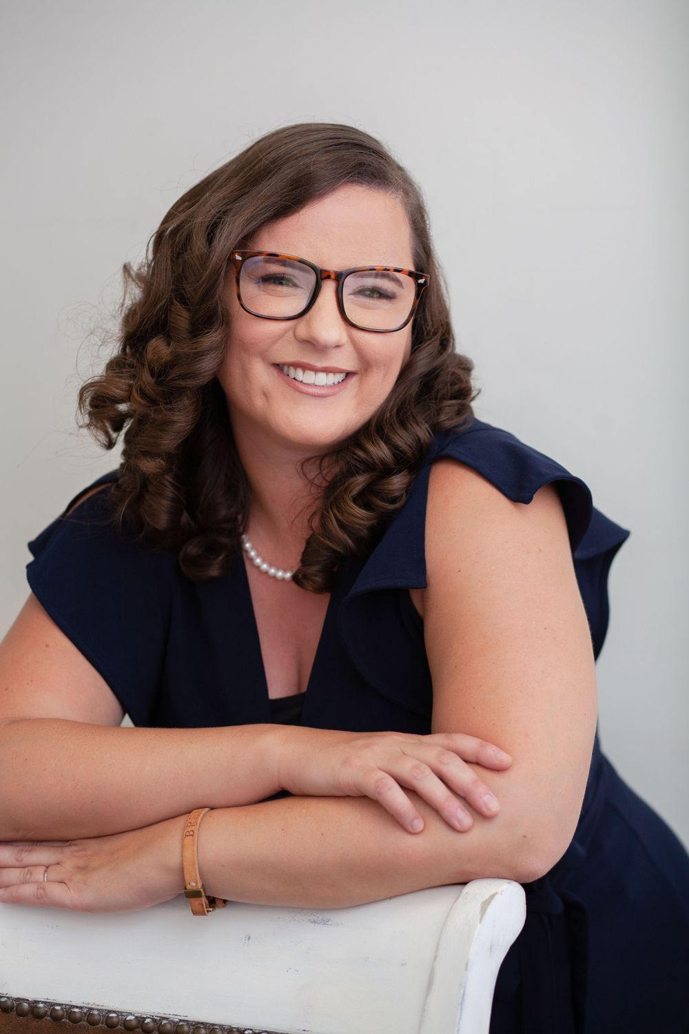 Headshot portrait of a woman wearing a blue dress and glasses