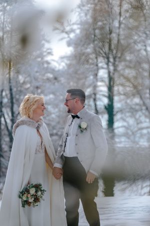Hochzeitsfotografie: Brautpaar steht sich im Schnee gegenüber, ruhiger Moment im winterlichen Licht im Umland von München.