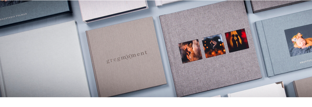 Collection of photo albums and prints displayed in grey studio setting.