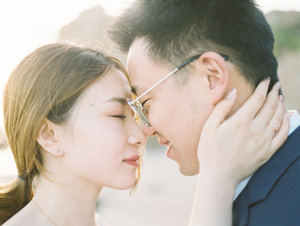 Romantic beach engagement photo with soft sunlight illuminating an intimate moment.