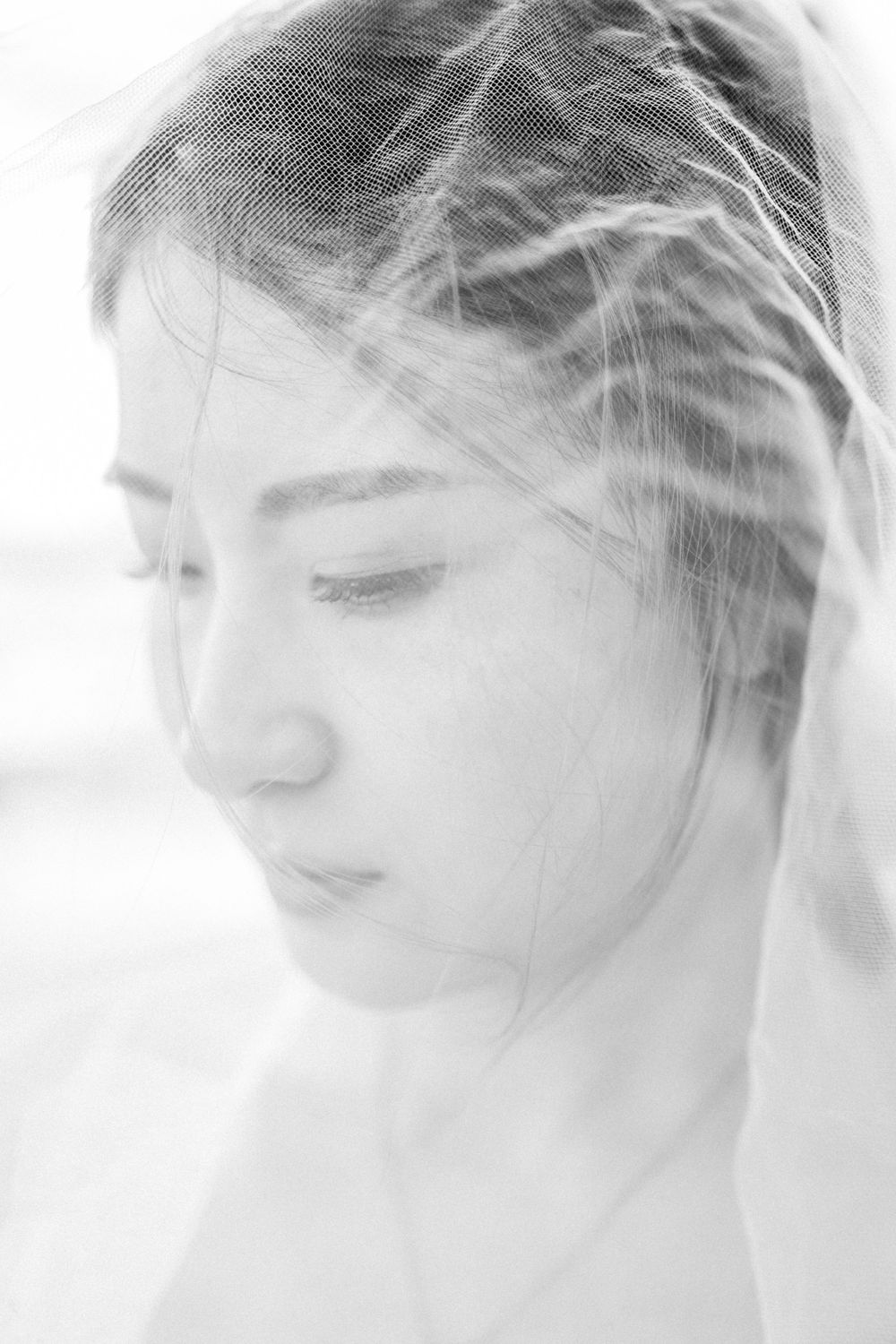 Ethereal portrait of a bride in soft focus with delicate veil and dreamy lighting effects.