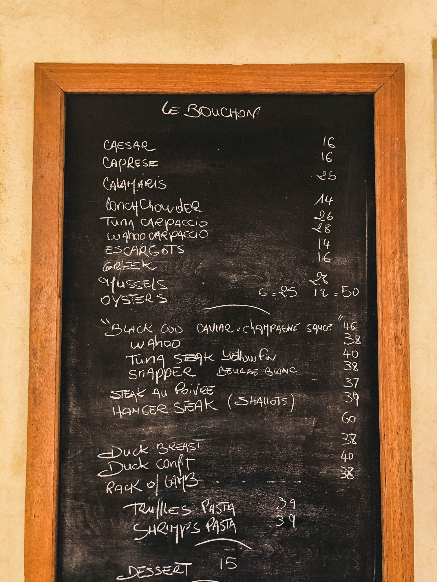 Restaurant menu written on black chalkboards displaying prices and food items.