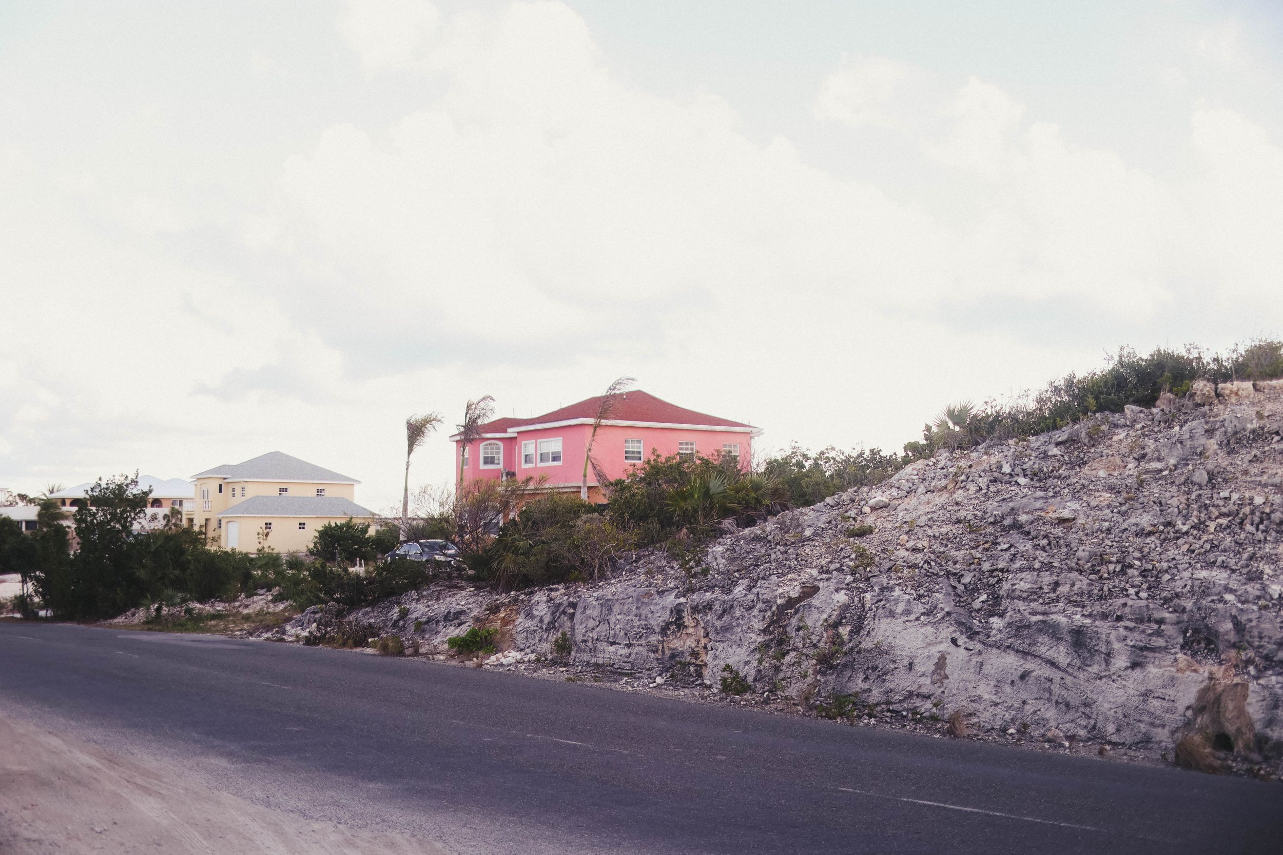 Panoramic view of a coastal road with white buildings and rocky terrain.