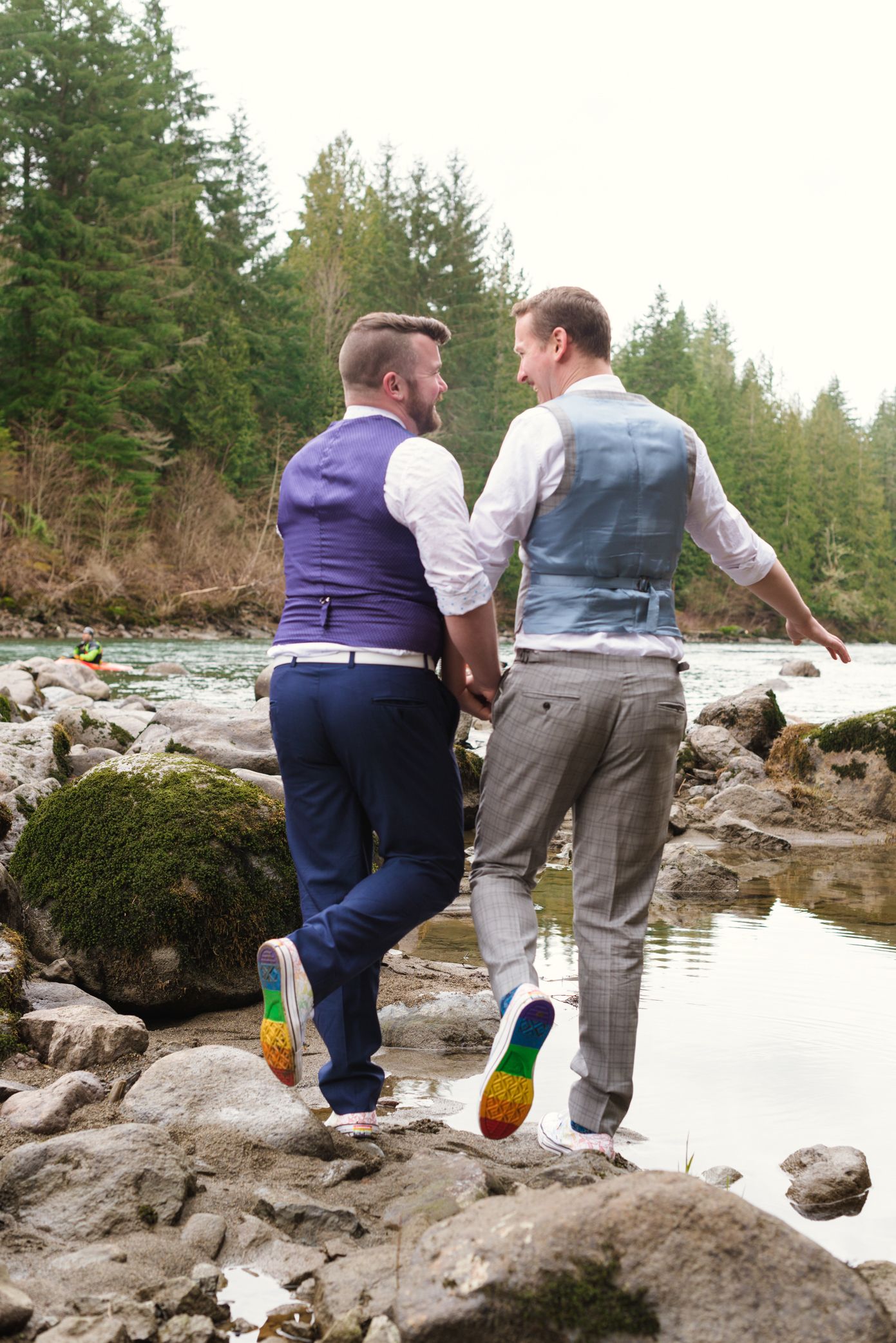 Couple sitting on rocky shoreline wearing coordinating outfits with rainbow socks.