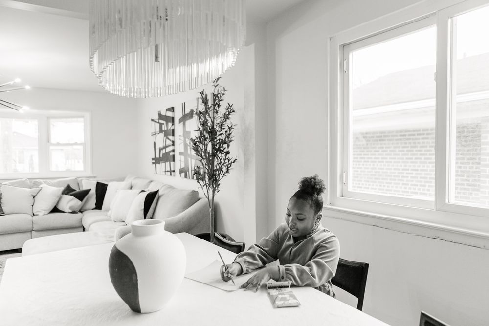 a black and white open view of a girl coloring in the dinning room table during an at home session in Queens, NY