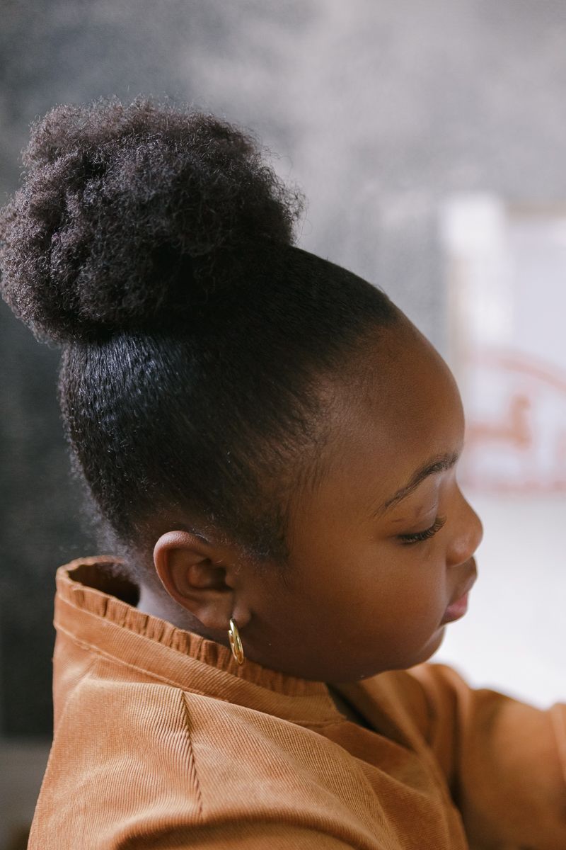 a close up view of a black girl's hair with beautiful light during a family session at home in Queens, NY