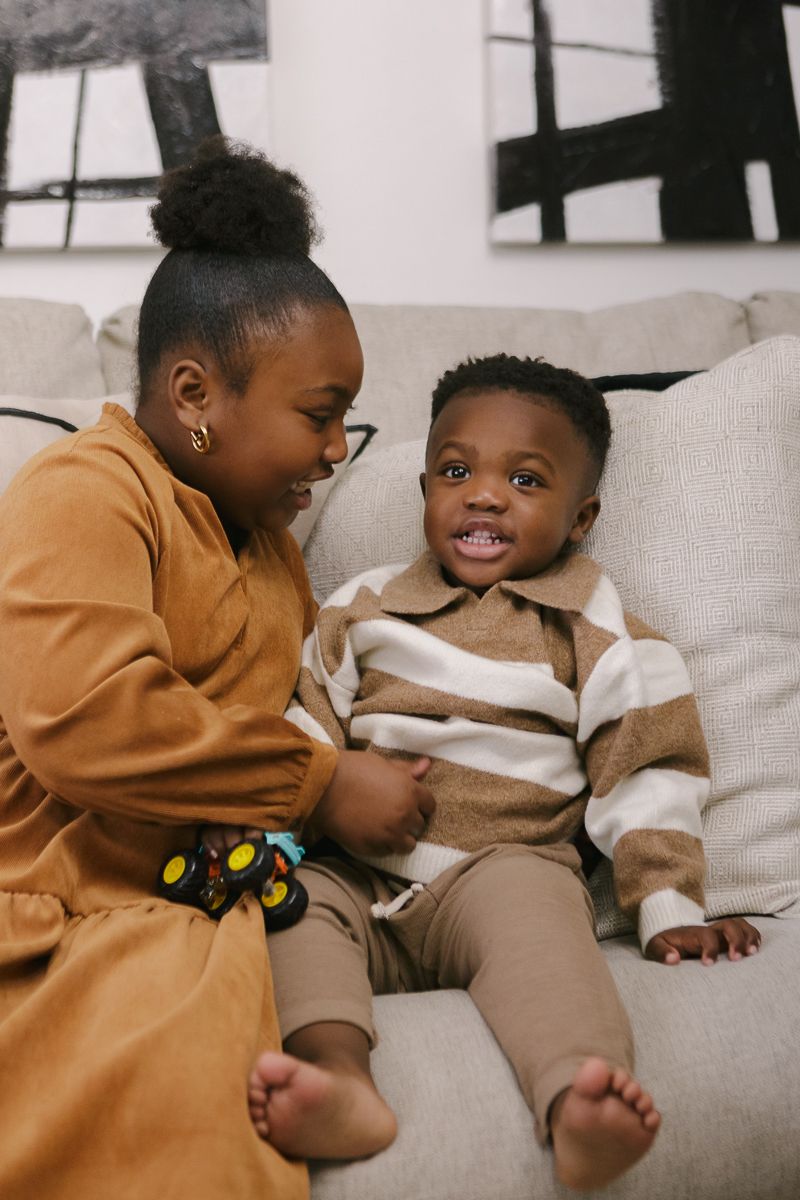 a girl and his little brother play candidly on the couch at their home in Queens, NY during a family session by Paula O