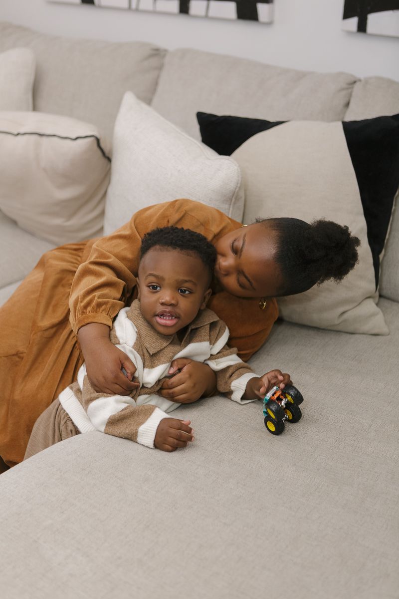 a candid moment of a girl kissing his little brother's head during a family session at home by Queens photographer Paula