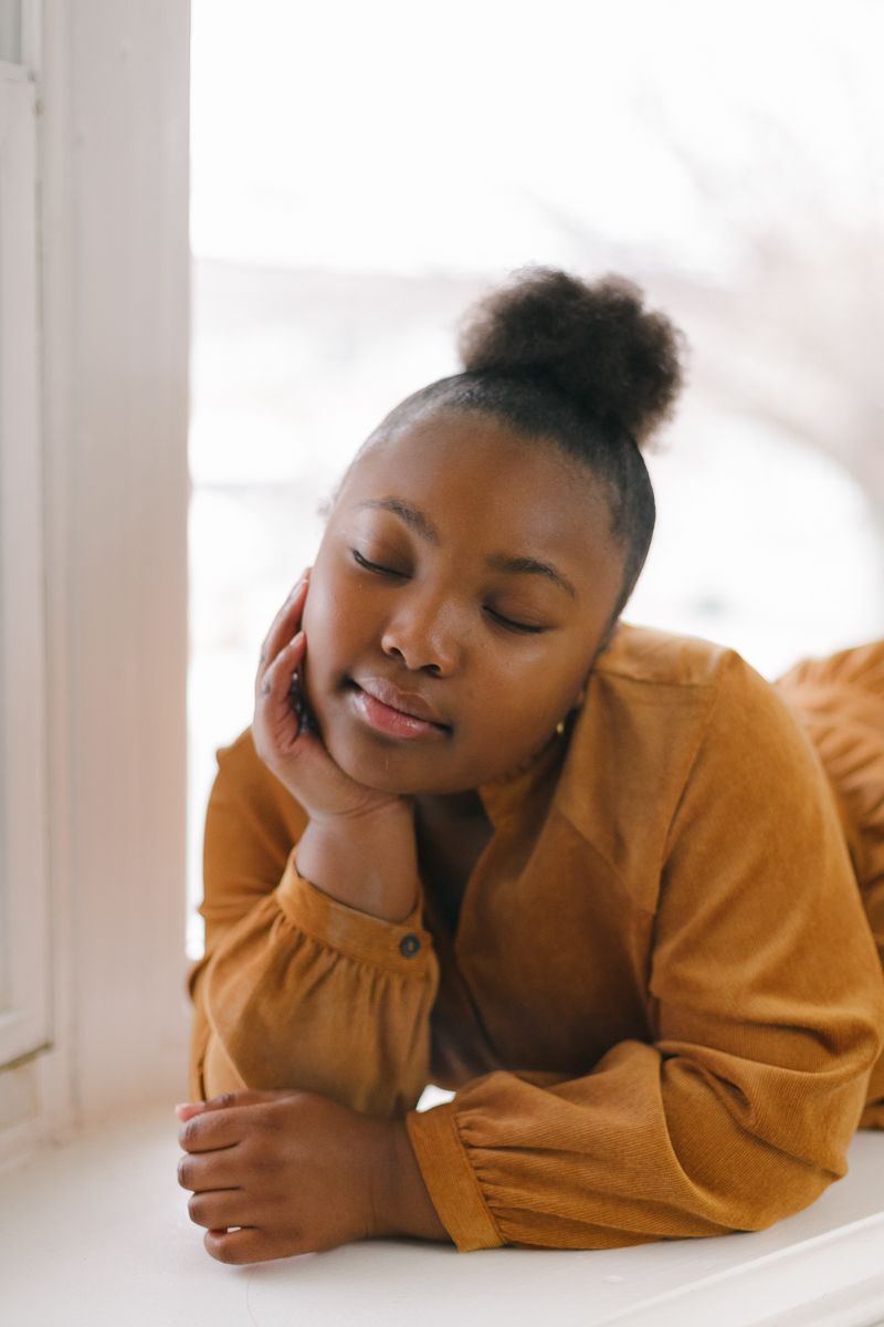 a close up view of a girl with closed eyes laying by a window by Paula Ortiz NYC family photographer
