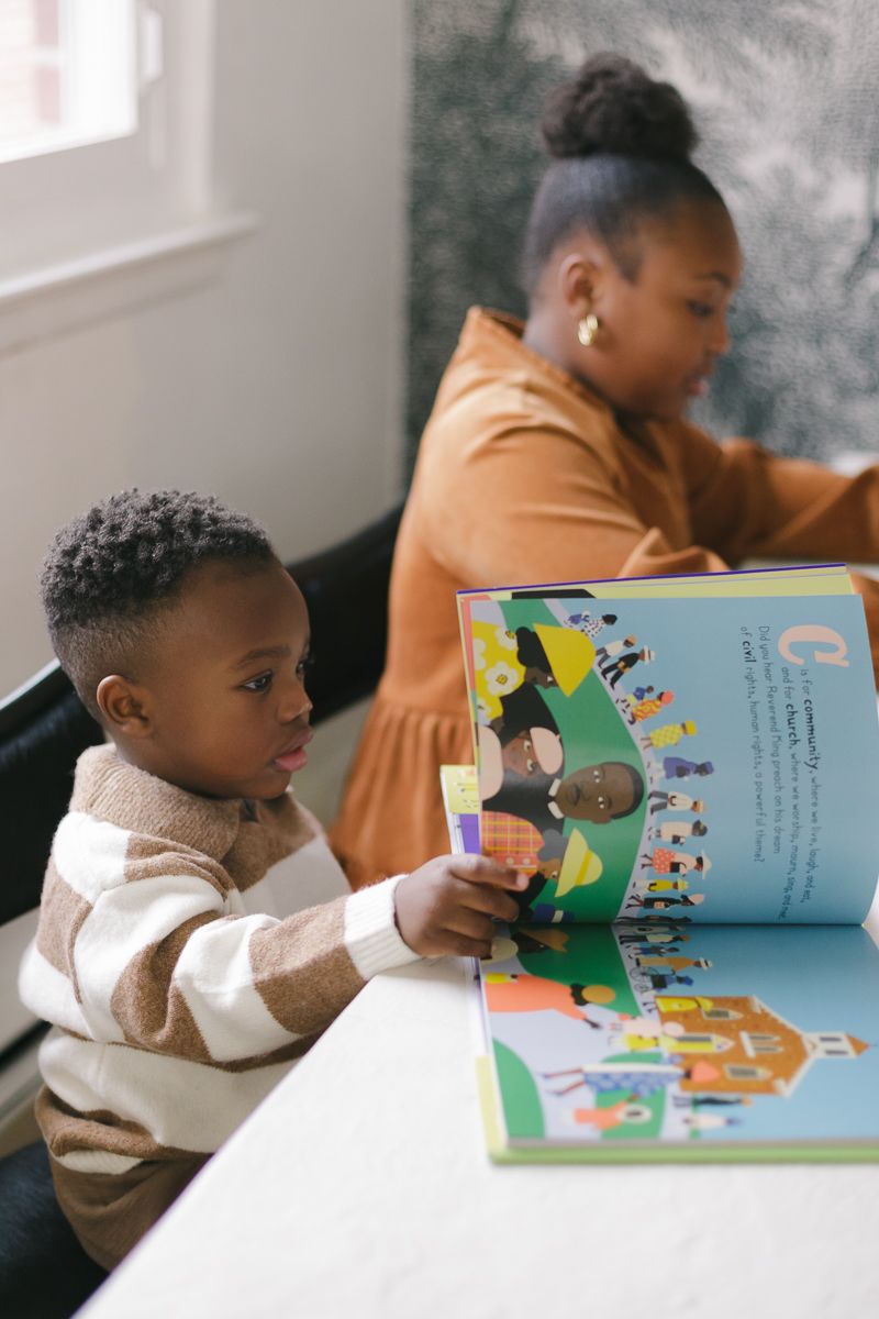 a little boy reads a book about African American history next to his sister, photo by Queens family photographer Paula O