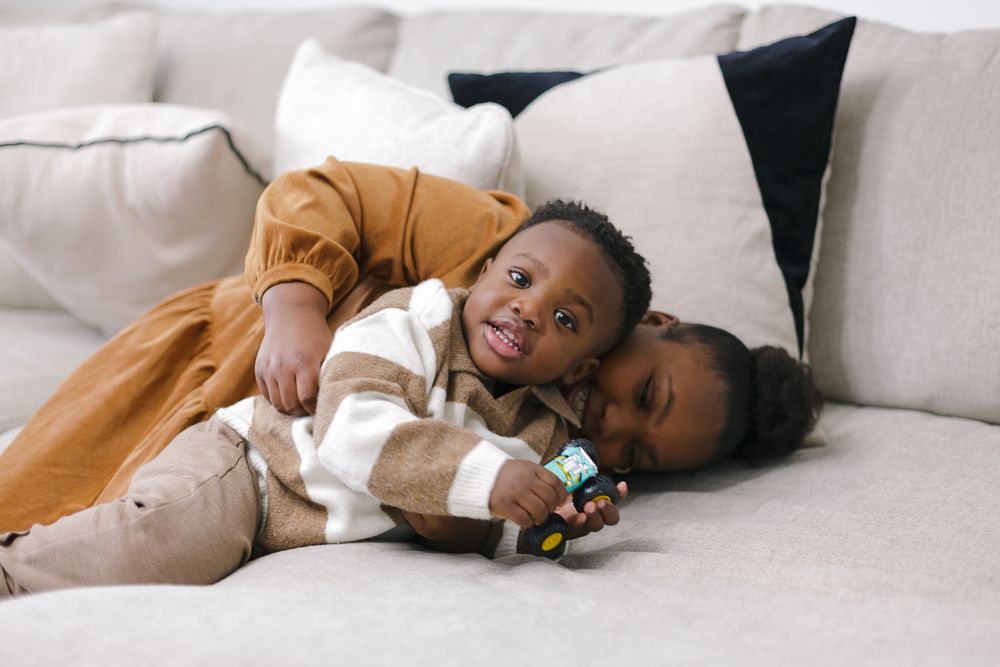 a candid moment of a girl holding his little brother's head during a family session at home by NYC photographer Paula O