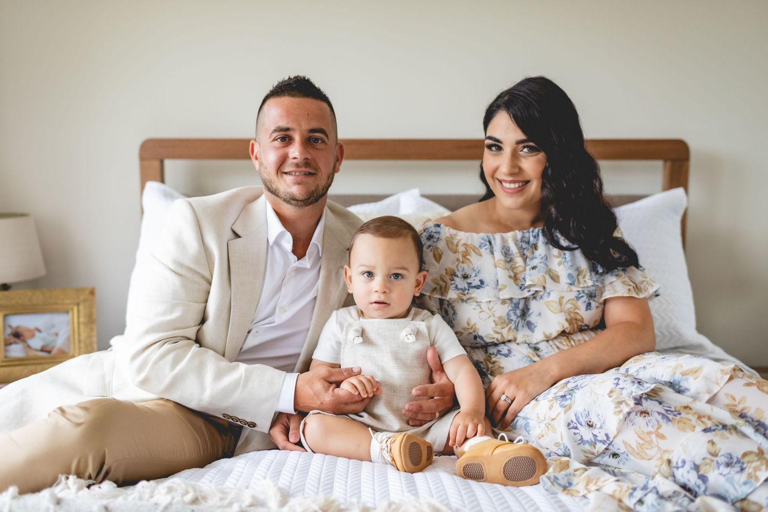 Family sitting together on bed with warm lighting.