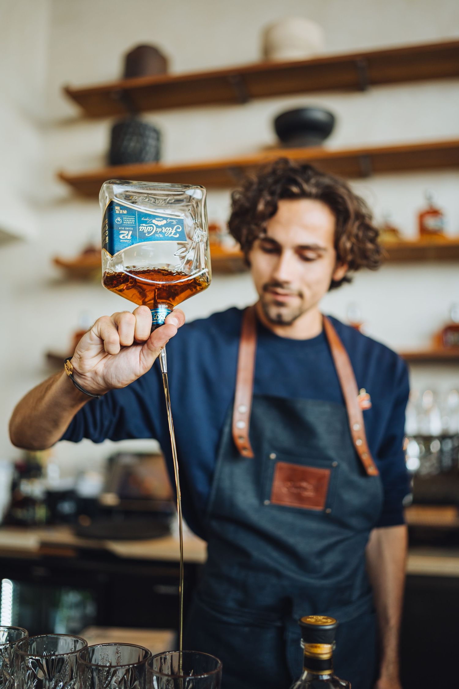 Bartender examining craft cocktail in stemmed glass at upscale bar.