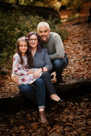 Portrait Session of Mother, Father, and daughter in the woods during the fall.