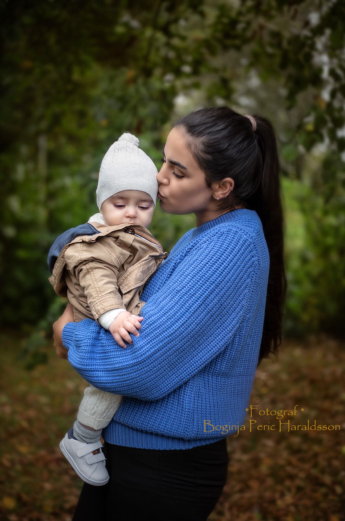 Mamma och bebis fotografering. Mamman pussar bebisen på huvudet.