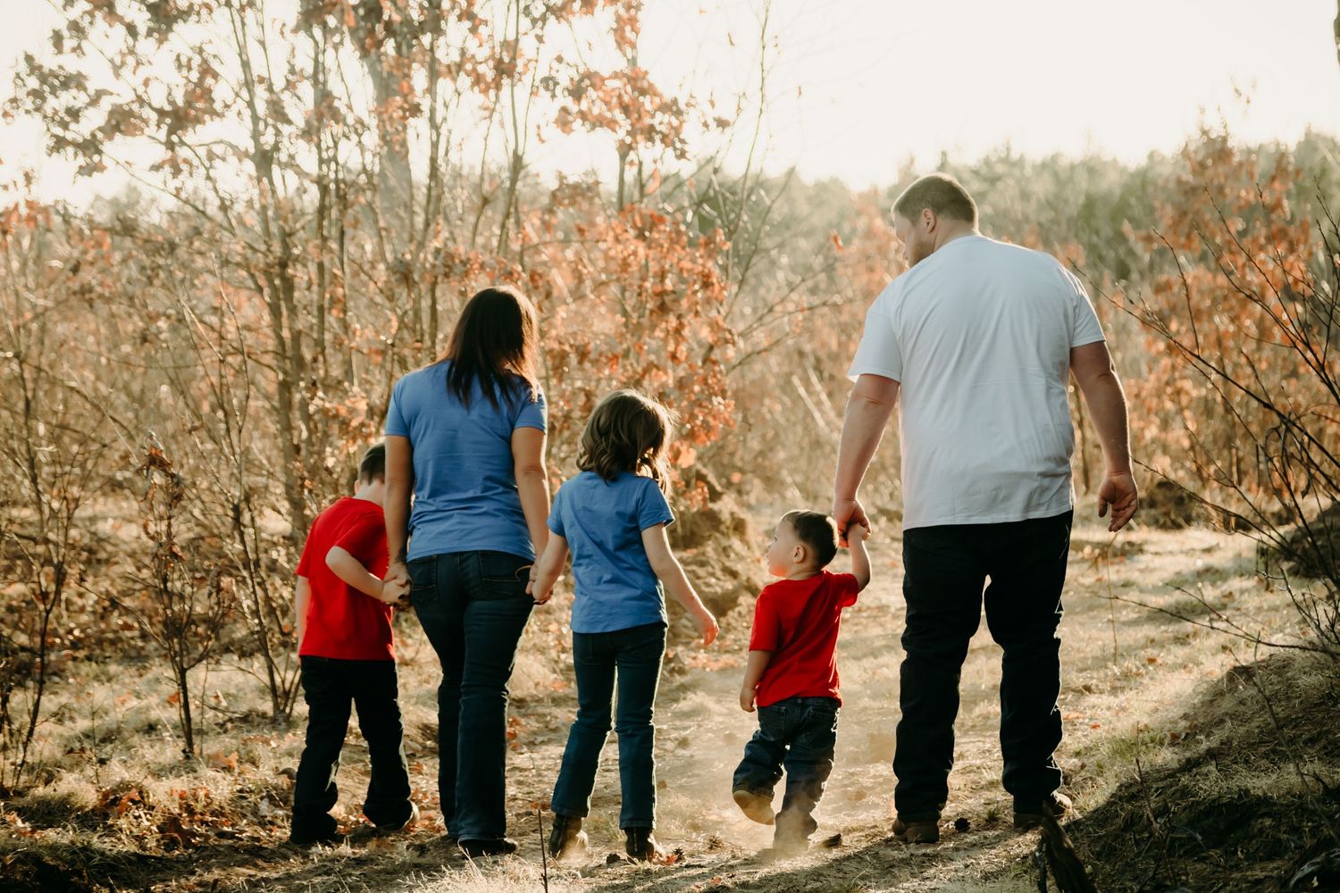 A family walks together along an autumn trail during golden hour.