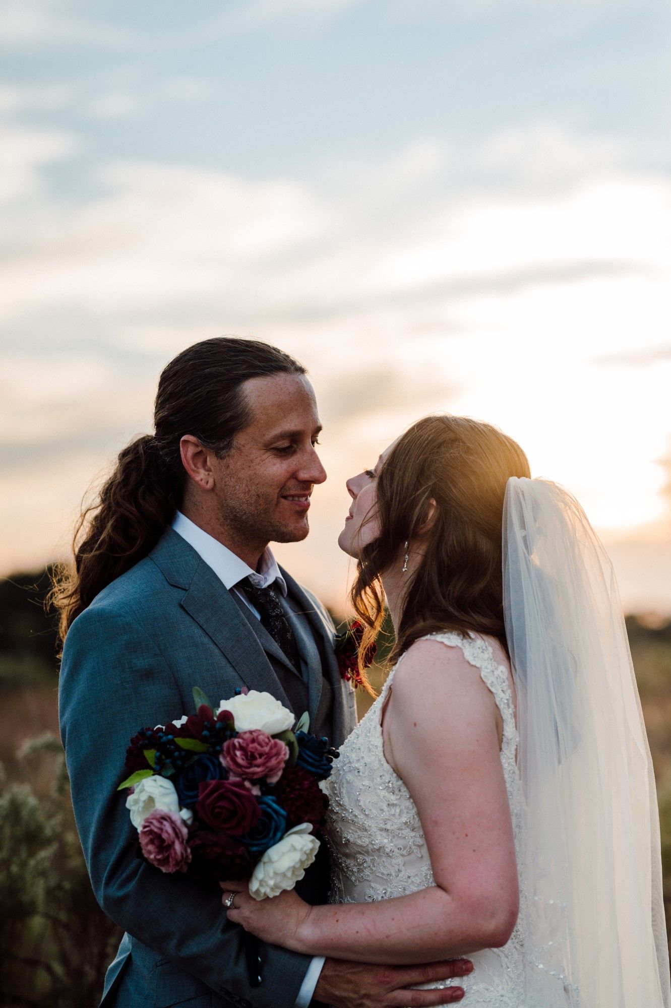 Bride and Groom hug with the sun setting.