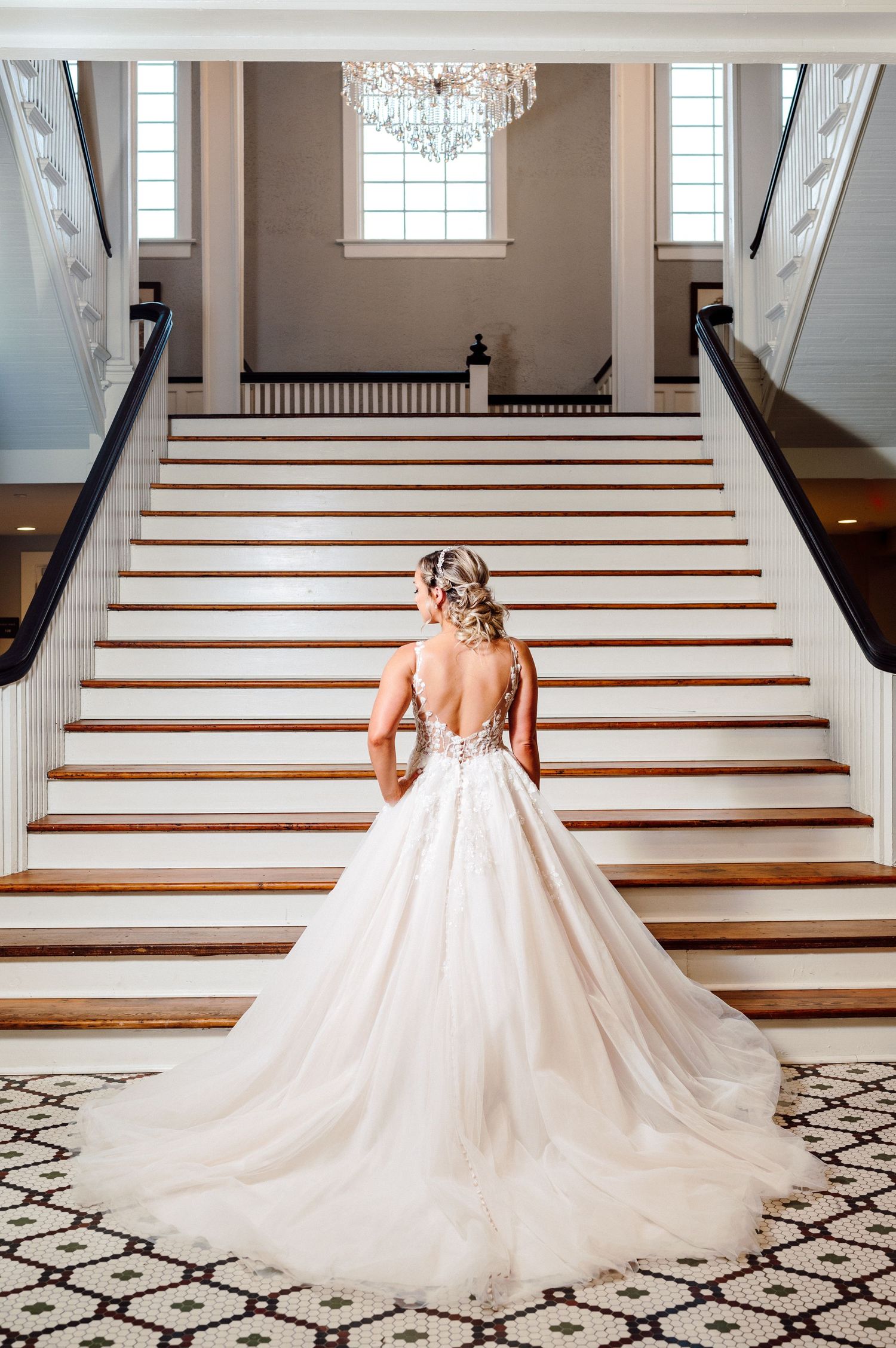 Bride stands Infront of ballroom stairs.