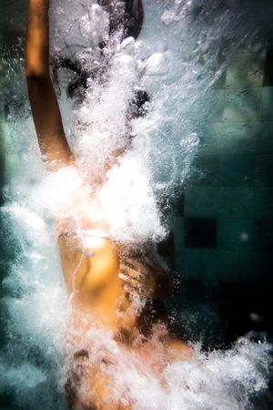 A woman's body falling through water surrounded by bubbles