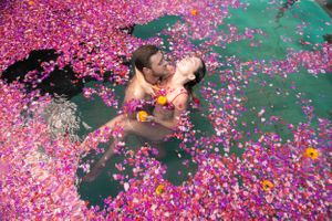 A couple embrace in a pool of flowers