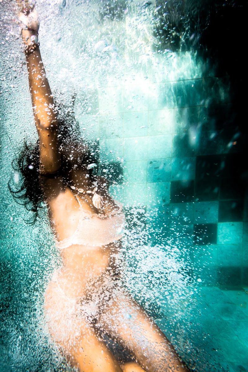 A girl falling through the water with one arm in the air