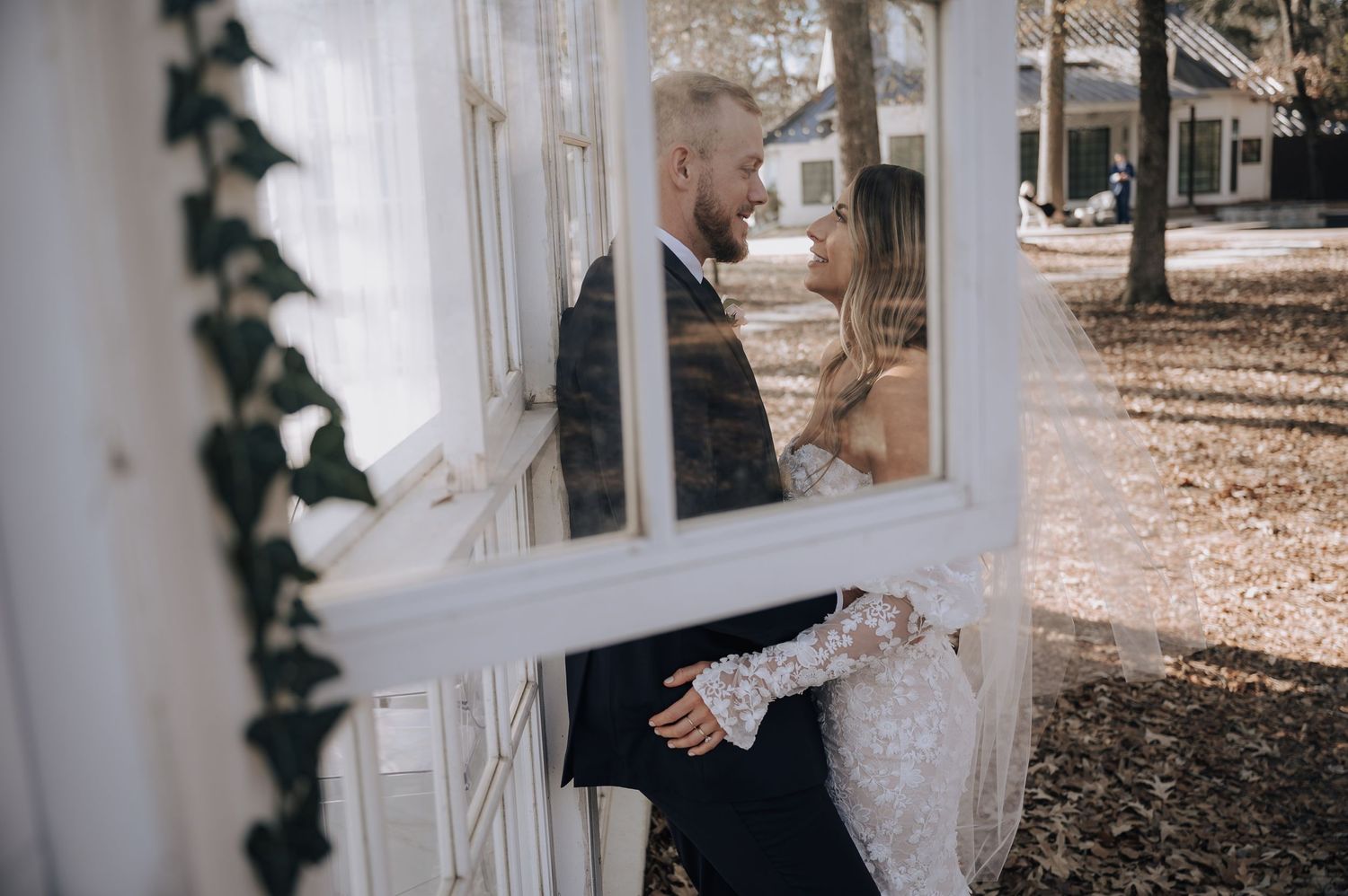 Romantic wedding photo through glass windows of couple embracing.