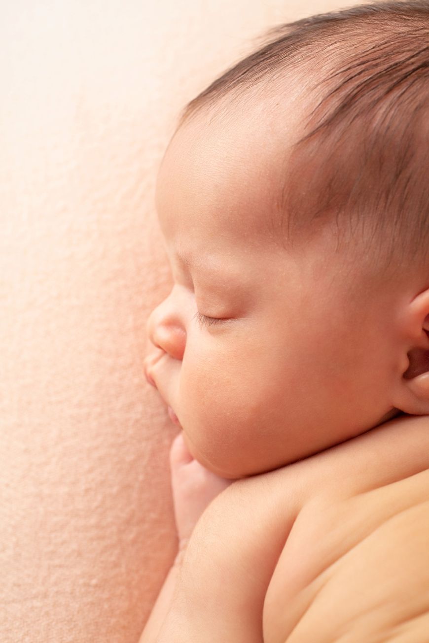 Peaceful sleeping infant resting on soft pink blanket in gentle natural light.