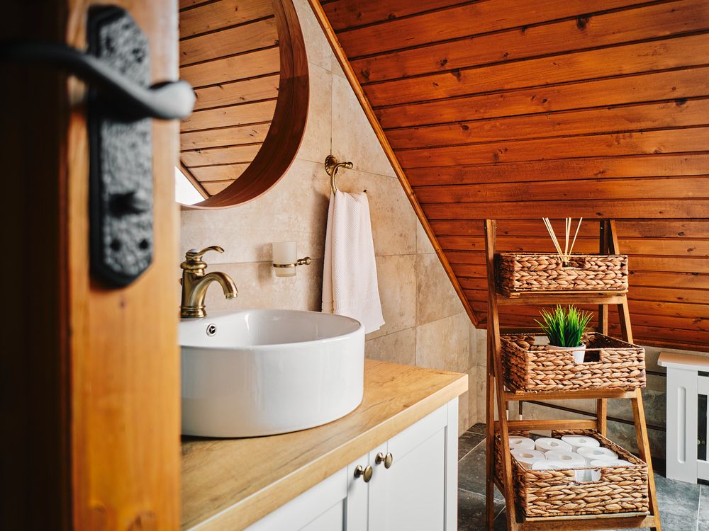 Modern bathroom with vessel sink and woven storage baskets against wooden plank walls.