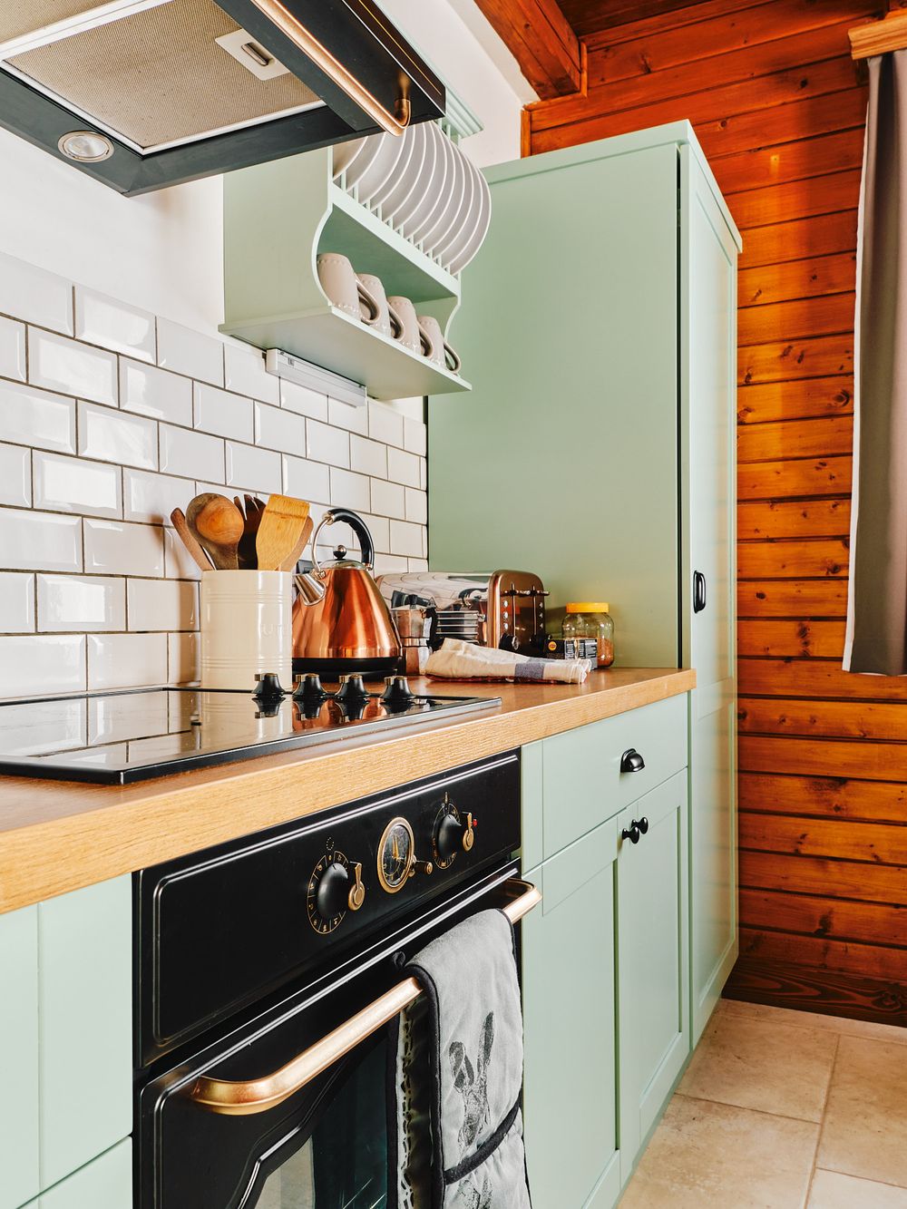 Modern mint green kitchen with wooden countertops and white subway tile backsplash.