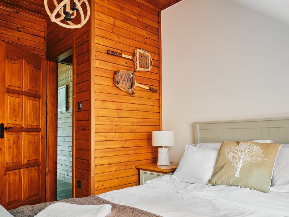 Cozy bedroom with wooden walls, upholstered headboard, and decorative wall accents.
