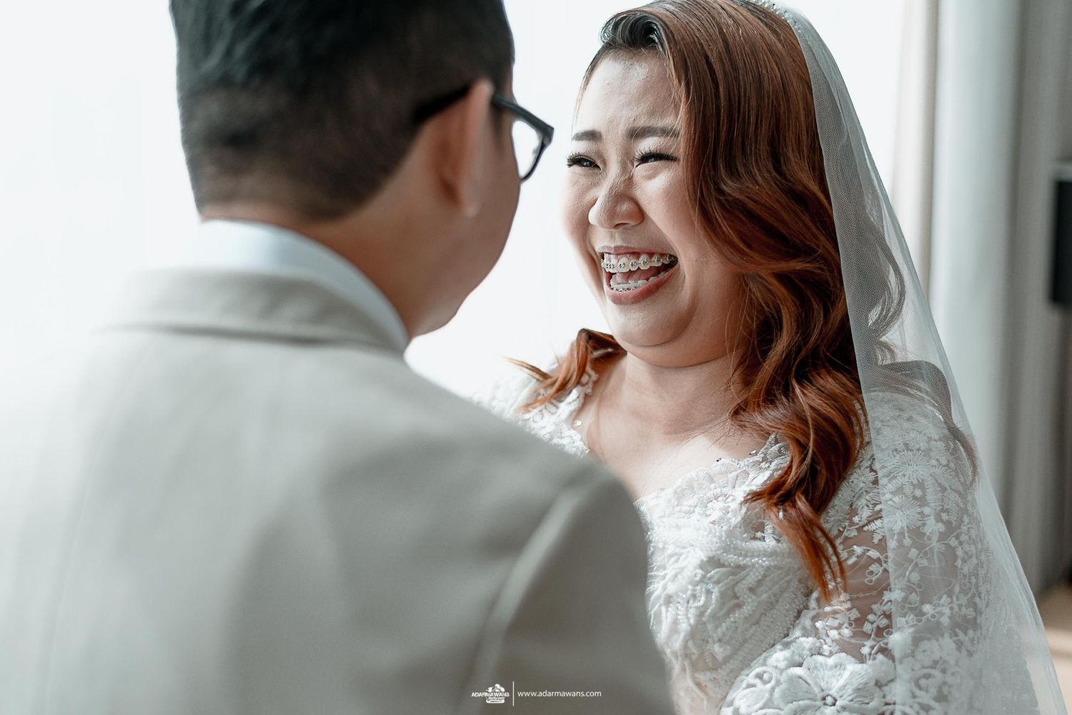 Joyful wedding moment captured in natural window light.