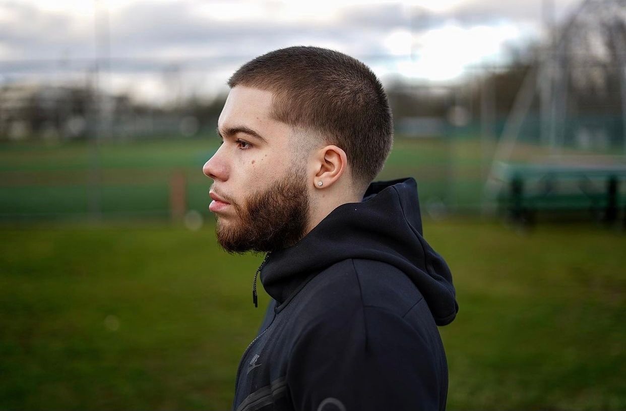 Client in a black hoodie walking outdoors on a cloudy day.