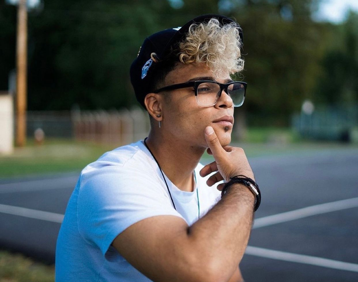 Person wearing glasses sitting outdoors in casual attire.