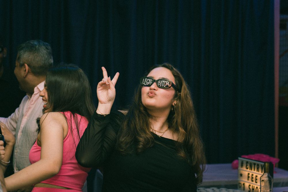 Person in black making peace sign gesture at a party.