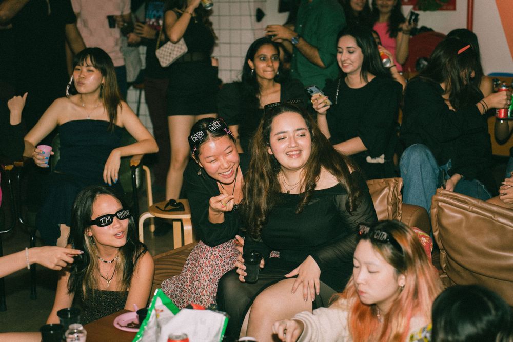 Energetic party scene with people dancing and laughing in a dimly lit room.