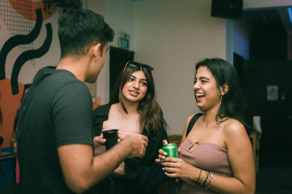 People enjoying drinks and conversation at a casual indoor gathering with artistic wall decor.