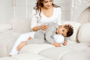 Parent comforting young child in white room with ornate decor.