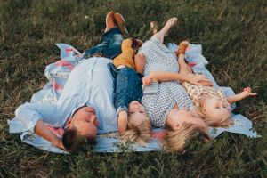 Children laying on a blanket in the grass during golden hour.