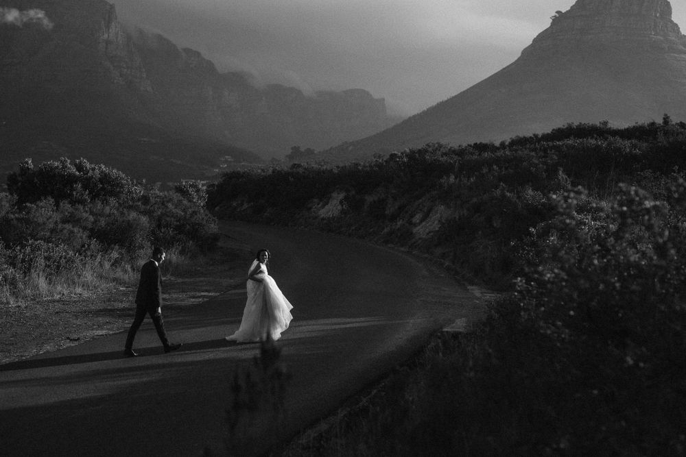 dramatic photo of a couple crossing the street in their wedding attire and dress on Signal Hill in Cape Town