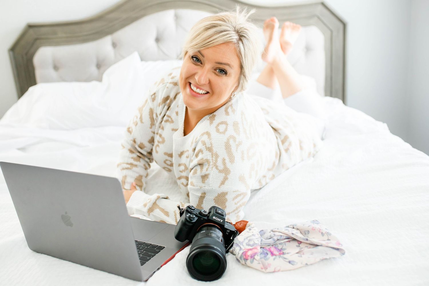 A woman sitting on a bed and using a laptop computer. Katie Gibbons Photography