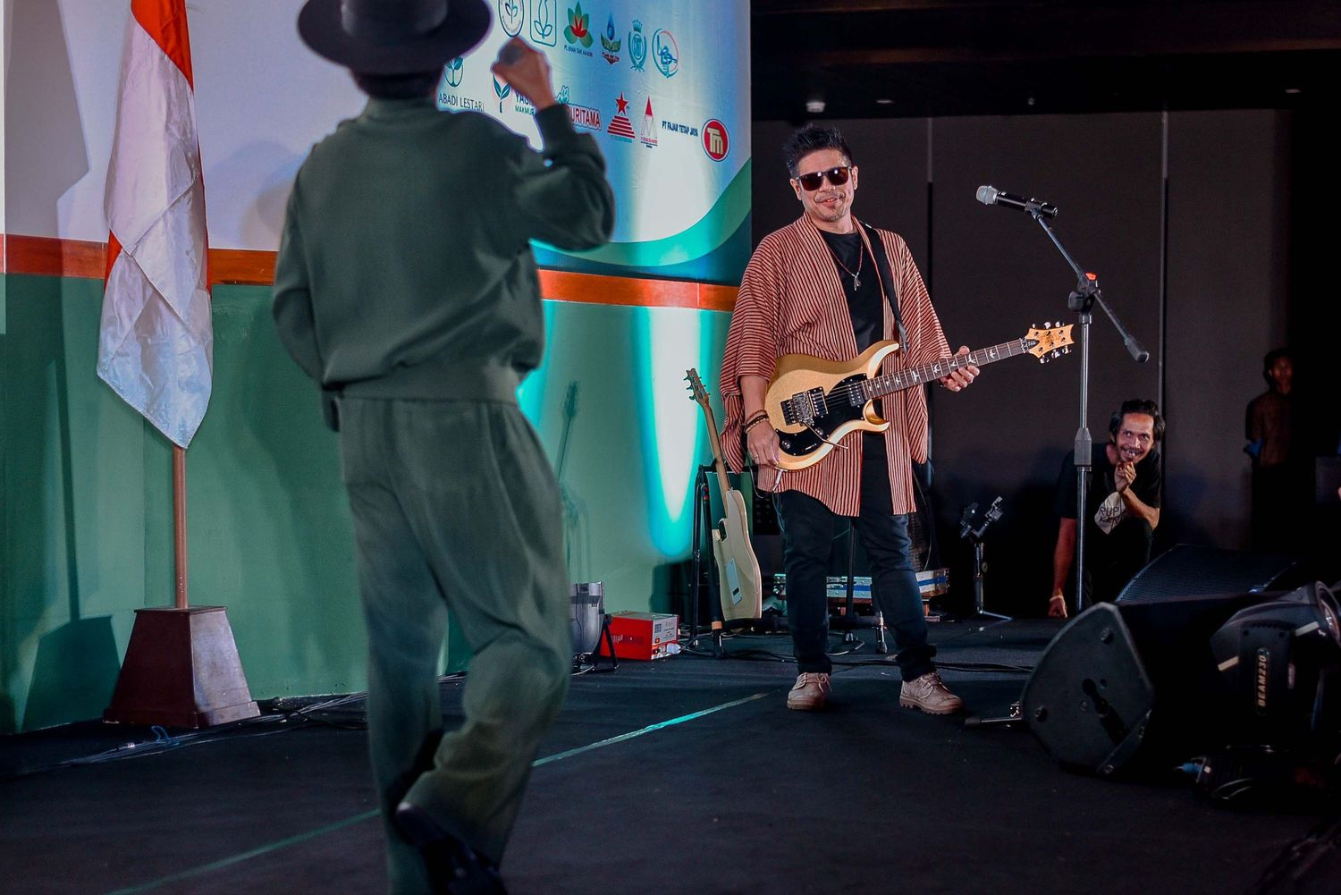 Musicians perform on stage with colorful lighting and dramatic silhouettes.