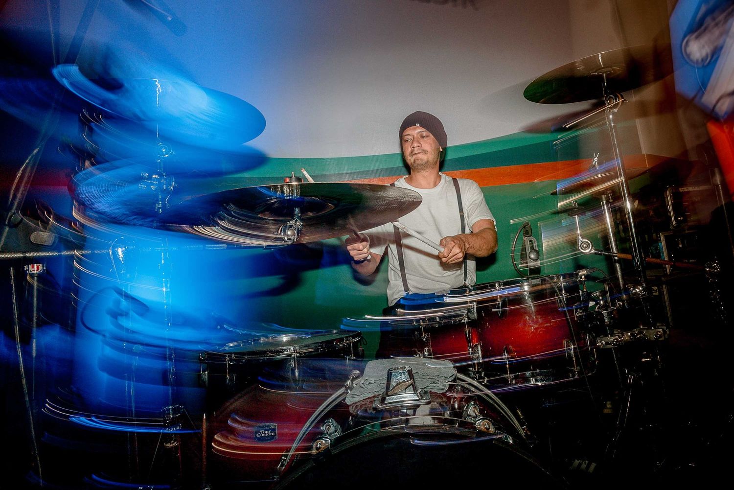 Drummer performs with motion blur and dramatic blue lighting creating dynamic visual effect on stage.