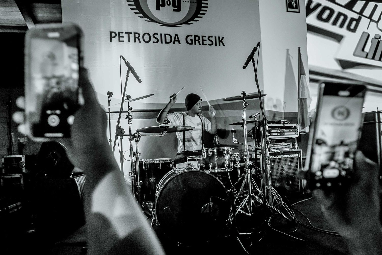 Black and white photograph of drummer performing at Petrosida Gresik event.