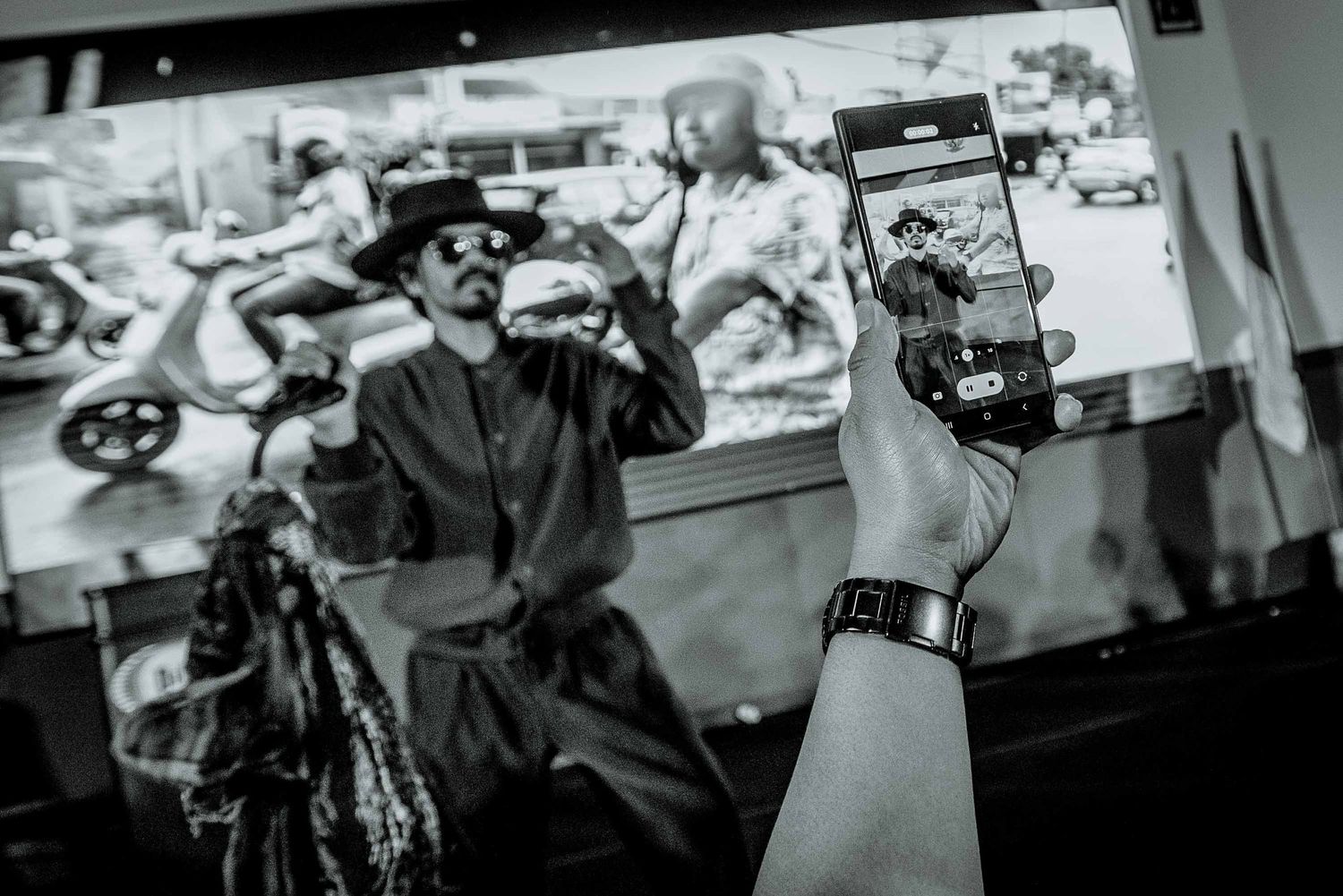 A black and white shot of a performer being filmed during a live show.
